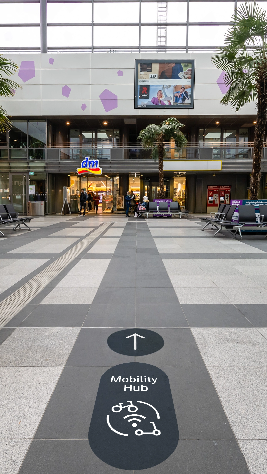 Nahaufnahme eines Piktogramms für den Mobility Hub der Deutsche Bahn, das den Übergang von Bahnreisen zu Mikromobilität wie E-Roller oder Fahrrad symbolisiert – auf dem Boden. Gestaltung durch die R211-Agentur.
