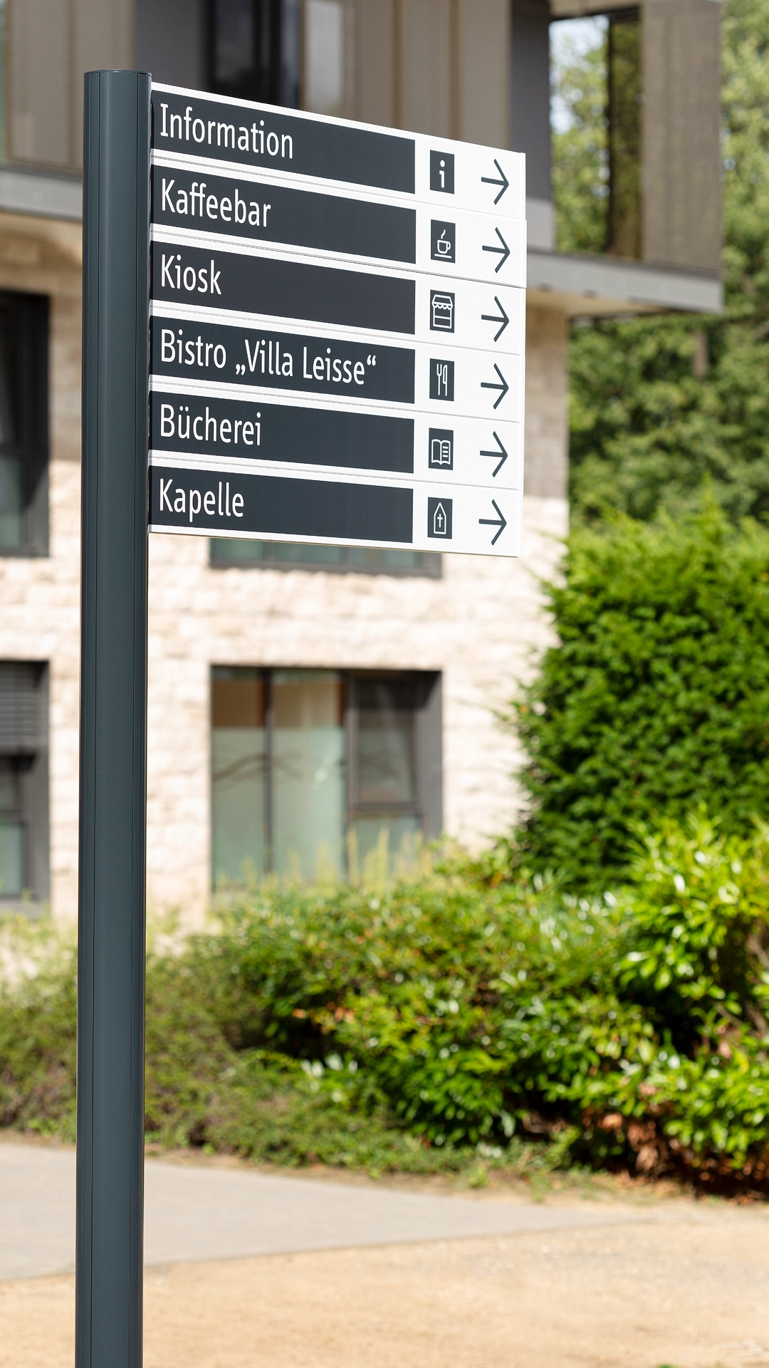 wegweiser auf dem klinikgelände mit beschilderung zu information kaffee bistro bücherei und kapelle im rahmen eines neuen orientierungssystems