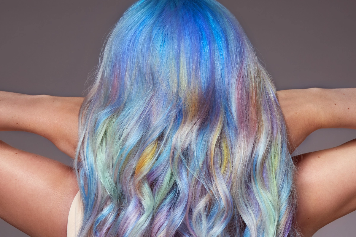Nahaufnahme des Hinterkopfs einer Frau mit langen Haaren in einem Farbverlauf von Blau bis Regenbogen – entstanden im Rahmen des Hair Haus Fotoshootings.
