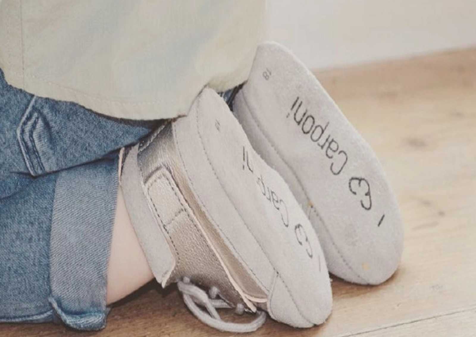Aufnahme eines krabbelnden Babys, bei der die Sohlen der Carponi-Schuhe sichtbar sind – mit gut erkennbaren Logo-Elementen: Schriftzug und Icon. Gestaltung durch R211-Agentur.