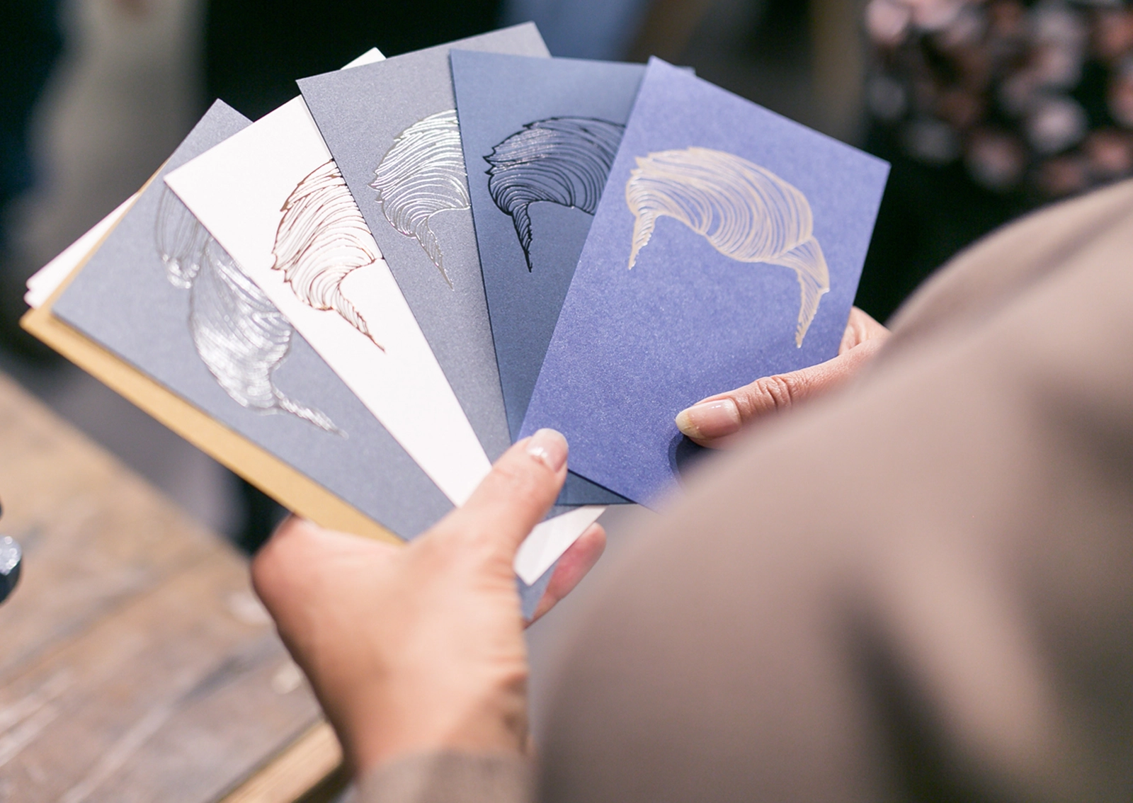 Eventbesucher hält verschiedene Papiermuster in der Hand und begutachtet die Haptik. Aufnahme vom Paper Playground Event von Freytag & Petersen, visuell gestaltet von der R211-Agentur.