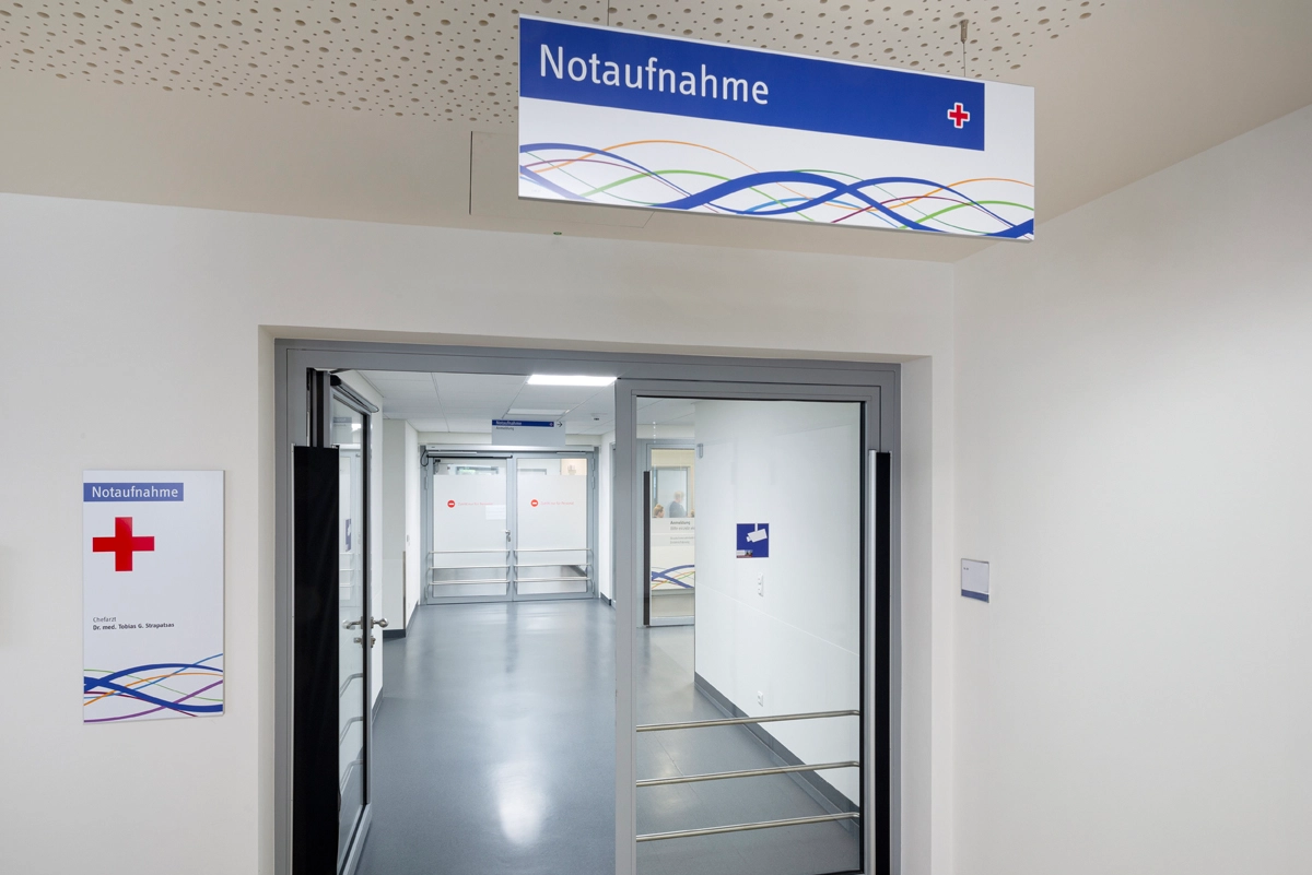 Innenaufnahme der Städtische Kliniken Mönchengladbach mit moderner Wegweisung zur Notaufnahme. Beschilderungskonzept und Umsetzung durch die R211-Agentur.