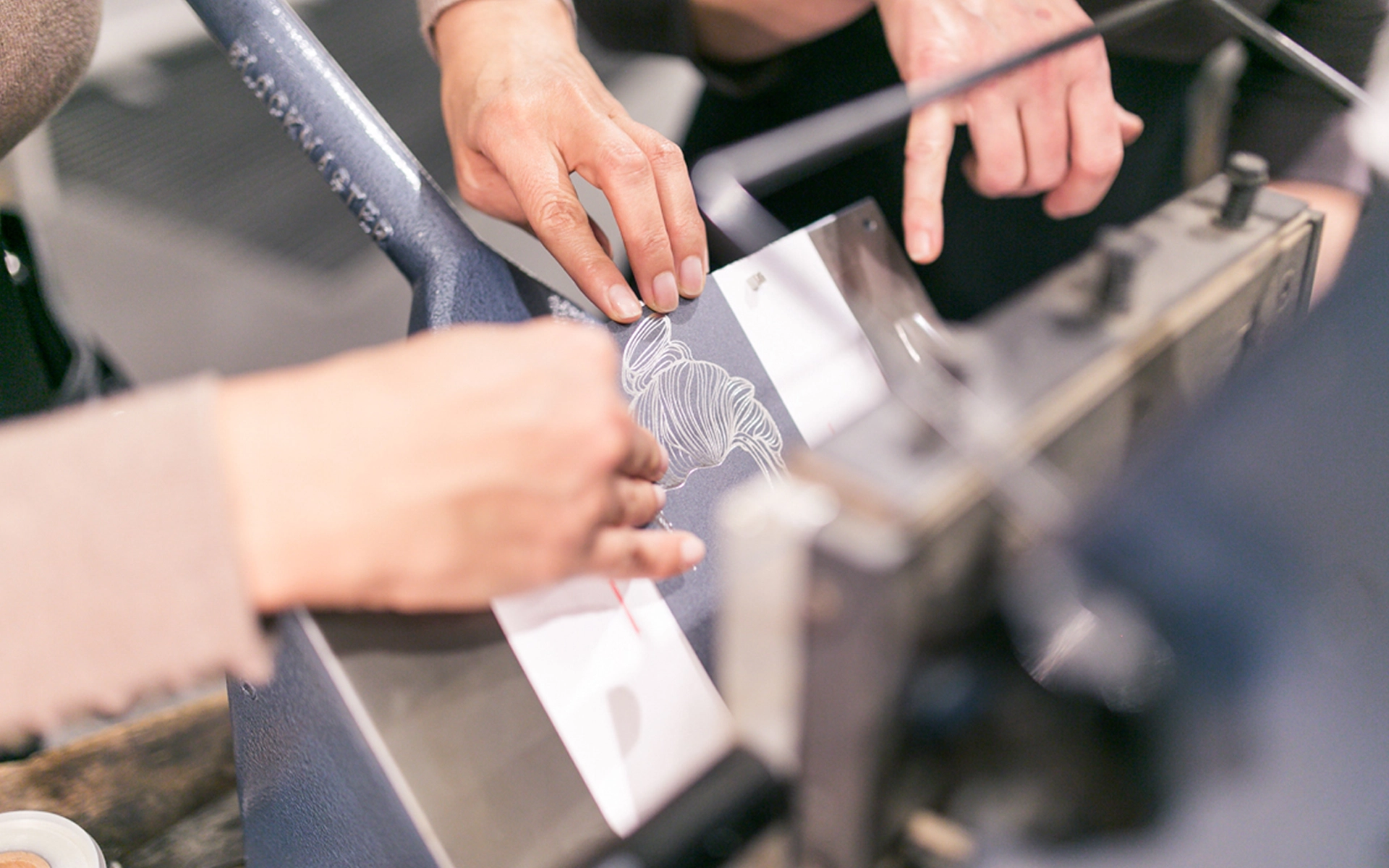 Aufnahme vom Paper Playground Event von Freytag & Petersen (Igepa Group), bei dem ein Eventbesucher an einer Heißfolienprägemaschine ein Motiv prägt.