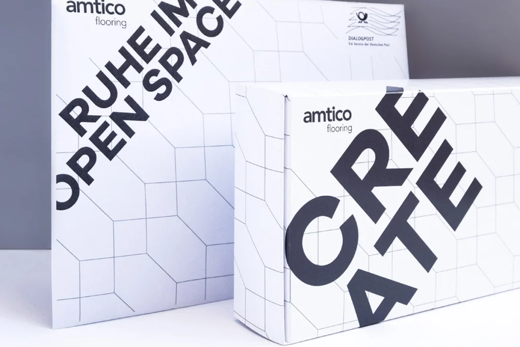 Ansicht beider B2B-Mailings von Amtico – eine hochwertige Versandbox und ein klassischer Briefumschlag – zur Veranschaulichung der unterschiedlichen Mailings für amtico Bodenbeläge.