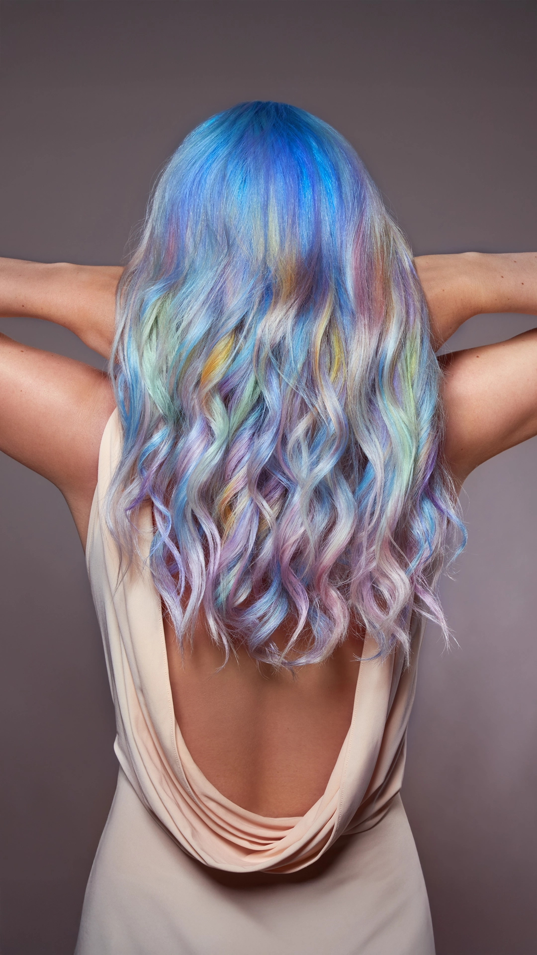Nahaufnahme des Hinterkopfs einer Frau mit langen Haaren in einem Farbverlauf von Blau bis Regenbogen – entstanden im Rahmen des Hair Haus Fotoshootings.
