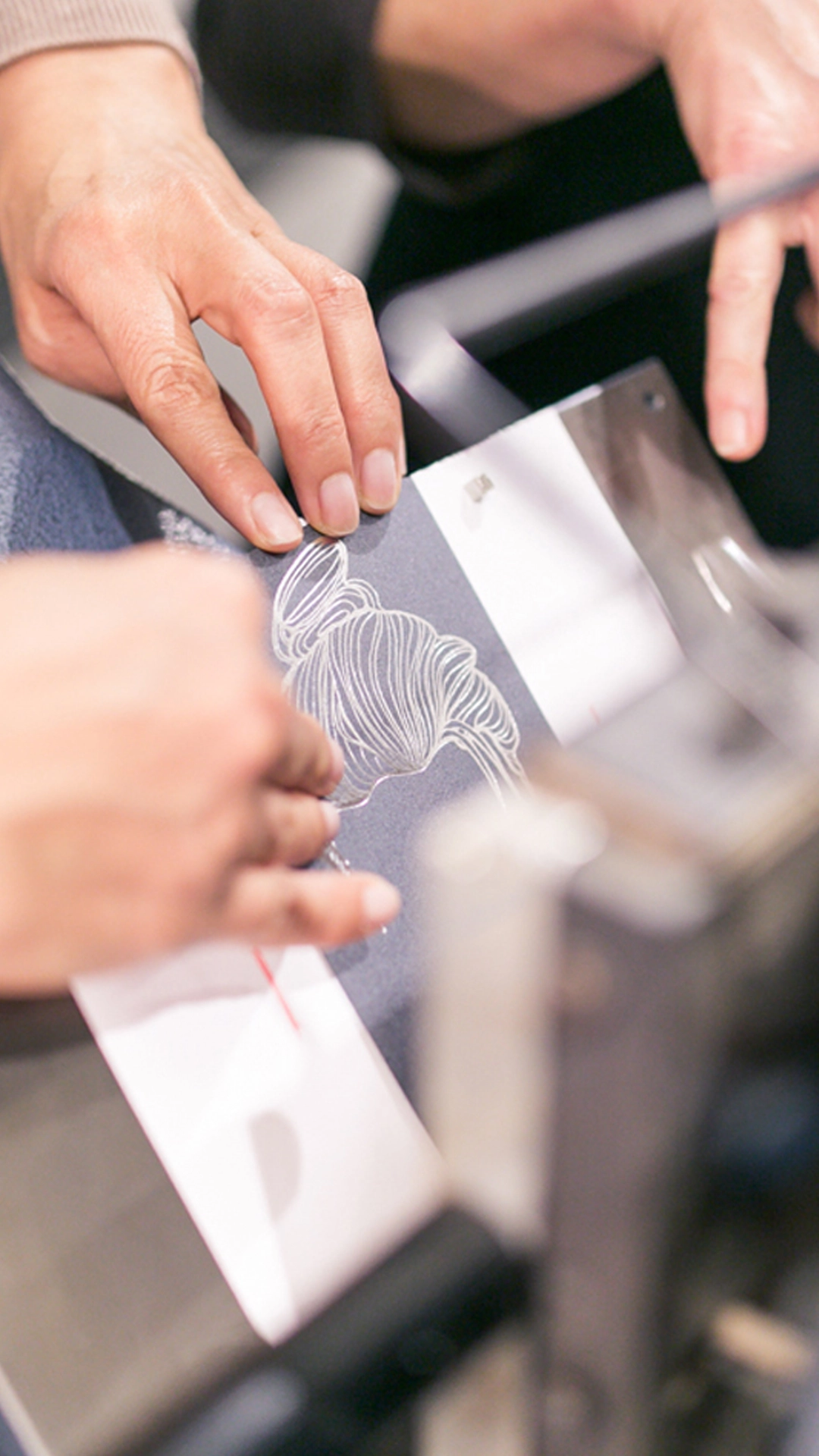 Aufnahme vom Paper Playground Event von Freytag & Petersen (Igepa Group), bei dem ein Eventbesucher an einer Heißfolienprägemaschine ein Motiv prägt.